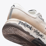 R1 Legacy trail running shoe, cream and tan colorway, "Transcend Distance" graffiti, ultrarunner design, durable sole.