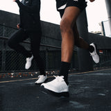 Two runners wearing P1 stability shoes with 3D Archrail technology, running on the road. #Color_white|black