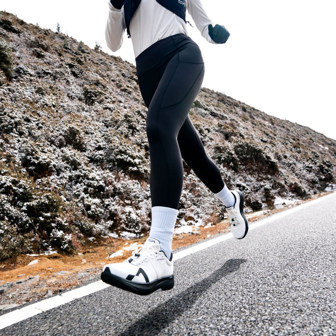 Mount to Coast R1 road running shoe in action, white shoe with black sole, runner on the road #Color_white|black