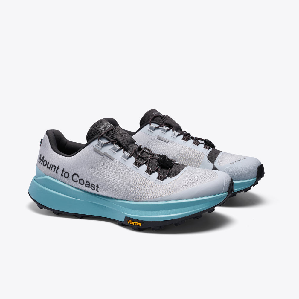 Mount to Coast T1 trail running shoe with light grey upper, aqua midsole, black outsole for trail running.