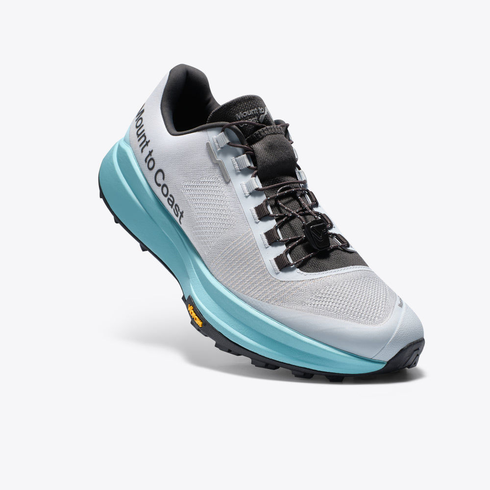 Mount to Coast T1 trail running shoe in light grey, aqua midsole, and black Vibram outsole, designed for trail running.
